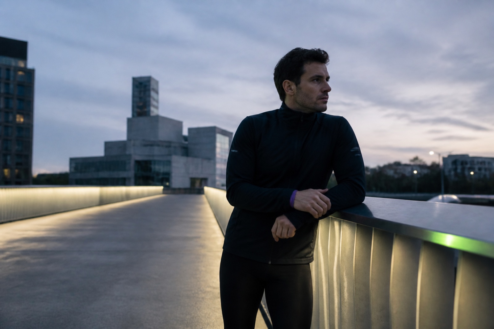 Runner pausing on a city bridge at dawn